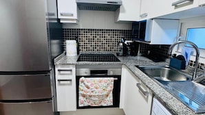 Une cuisine moderne dotée d’appareils électroménagers en acier inoxydable, d’un revêtement mural en carreaux et de meubles blancs.
