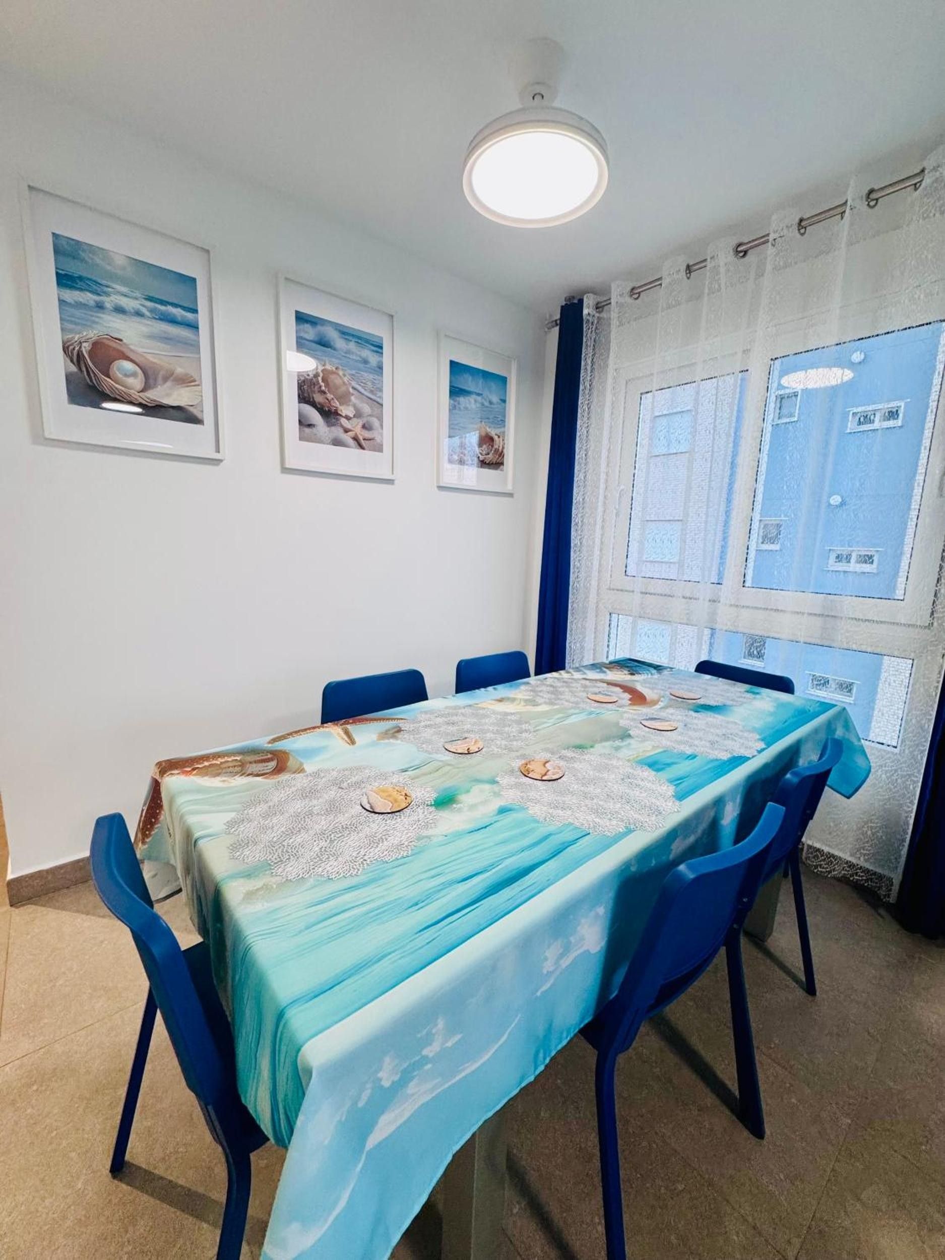Ein Essbereich mit einem Tisch für sechs Personen, blauen Stühlen und gerahmten Bildern an der Wand.