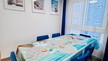 Een eethoek met een tafel voor zes personen, blauwe stoelen en wandelingen met afbeeldingen.