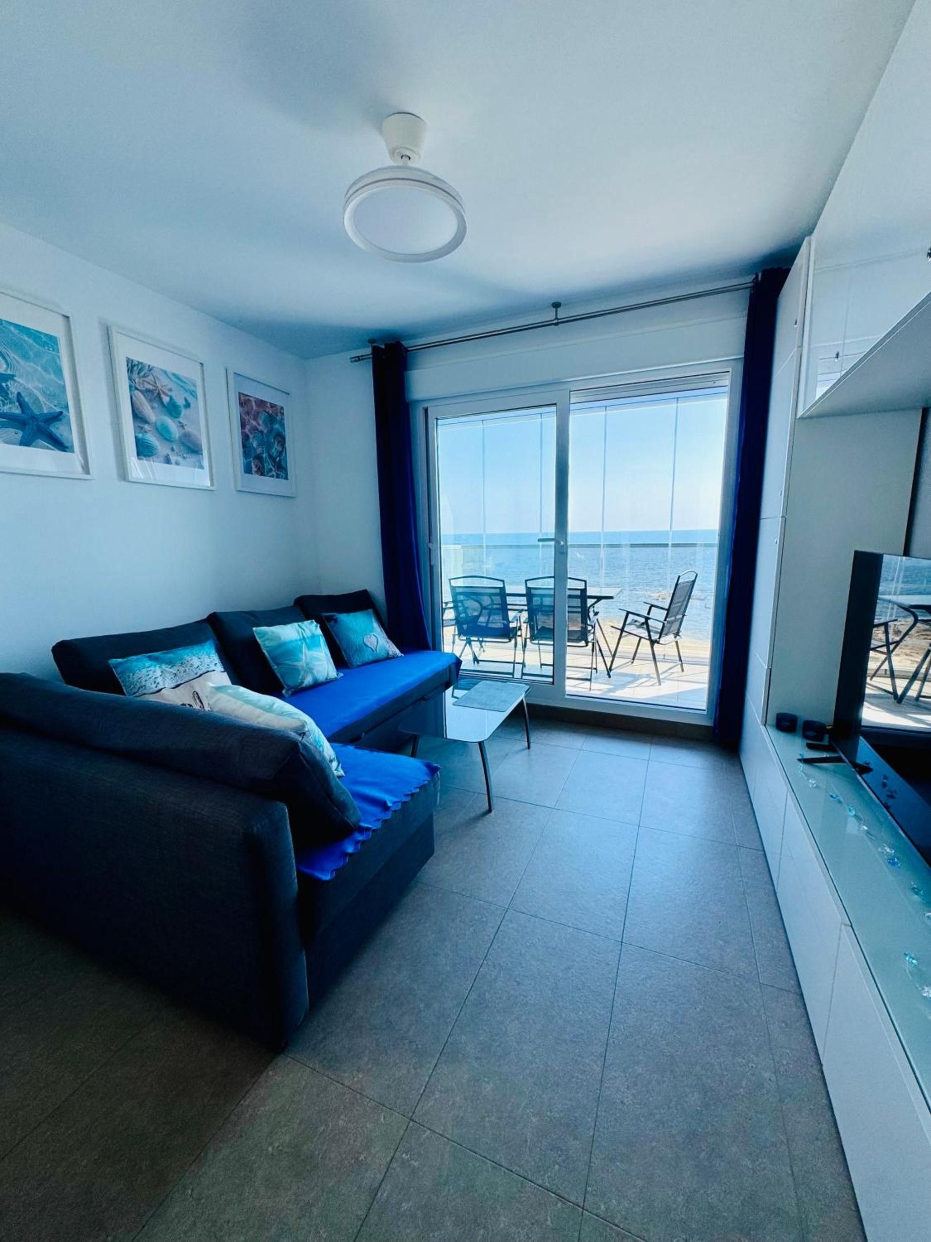 Ein modernes Wohnzimmer mit einer Couch, einem kleinen Tisch und einem Balkon mit Meerblick.