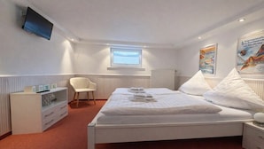 A hotel room with a bed, a chair, a TV, a window, and a poster on the wall. - Holiday apartment with 3 bedrooms (Norderney)