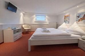 Ein Hotelzimmer mit Bett, Stuhl, Fernseher, Fenster und einem Poster an der Wand.