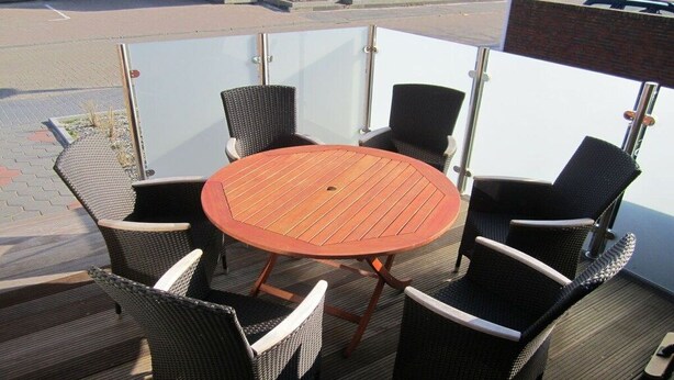 An outdoor patio with a round wooden table and four wicker chairs. - Holiday apartment with 3 bedrooms (Norderney)