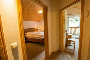 A bedroom with a wooden ceiling, a bed, a nightstand, and a window.