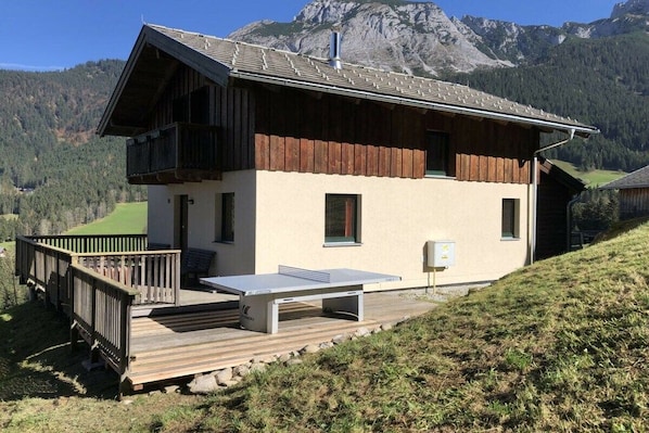 Eine Chalet mit einer Holterrasse und einem Tischtennisplatten.