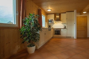 A kitchen with wooden cabinets, a microwave, and a potted plant. - Cabin in Annaberg with swimming pool (Annaberg)