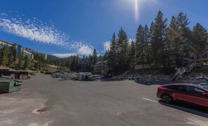 A parking area with RVs and cars, surrounded by trees and buildings.