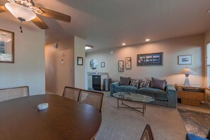 A living room with a dining table, sofa, and a ceiling fan.