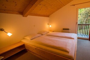 A bedroom with a wooden ceiling, a bed with white bedding, a nightstand, and a window with a view of trees. - Cabin in Annaberg with swimming pool (Annaberg)