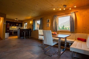 A cozy interior with a dining area, a sofa, and a kitchen in the background. - Cabin in Annaberg with swimming pool (Annaberg)