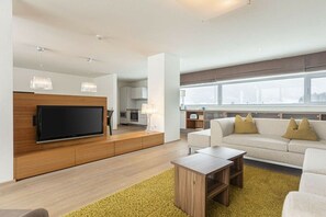 A modern living room with a flat-screen TV, a sofa, a coffee table, and a kitchen in the background. - Apartment in Radstadt with swimming pool (Radstadt)