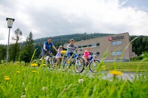 A family riding bicycles in front of a building labeled 'TAUERN RESIDENCE.' - Apartment in Radstadt with swimming pool (Radstadt)