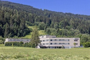 A modern hotel with a flat roof and a two-story structure, surrounded by a lush green landscape and a forested hill. - Apartment in Radstadt with swimming pool (Radstadt)