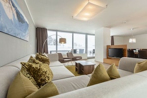 Una sala de estar moderna con un sofá, sillones, una mesa de centro y un televisor.