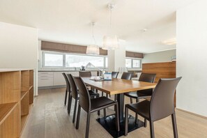 A modern kitchen with a dining table and chairs, wooden cabinets, and pendant lighting. - Apartment in Radstadt with swimming pool (Radstadt)
