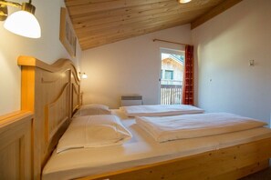 Une chambre avec deux lits, des têtes de lit en bois, une fenêtre avec des rideaux et un plafond en bois.