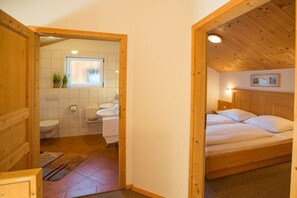 A wooden room with a bed, a window, and a bathroom visible through an open door. - Cabin in Annaberg with swimming pool (Annaberg)