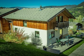 Un chalet en bois doté d’un balcon, d’une terrasse et offrant une vue sur le paysage environnant.