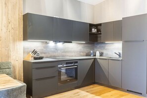 A modern kitchen with built-in appliances, a wooden dining table, and a grey countertop. - Apartment in Fügen with swimming pool (Fügen)