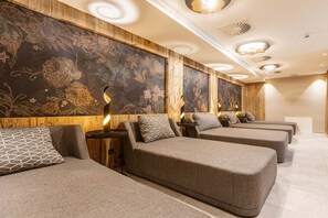 Una sala de spa amb diverses camilles de massatge, panells de fusta i un mural floral gran a la paret.