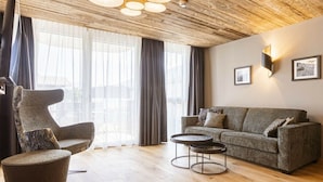 Een moderne woonkamer met een houten plafond, een bank, een fauteuil en een salontafel.