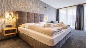 Een hotelkamer met een groot bed, een hoofdbord, nachtlampjes en uitzicht op de stad.