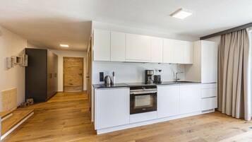 A modern kitchen with white cabinetry, a built-in oven, and a coffee maker.