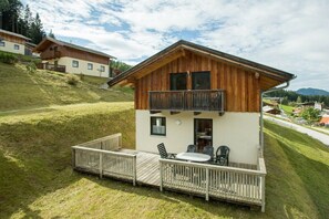 Un chalet en bois doté d’un balcon, d’une terrasse et d’un coin repas.