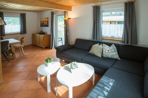 A living room with a sofa, two small tables, a cabinet, and a painting on the wall. - Cabin in Annaberg with swimming pool (Annaberg)