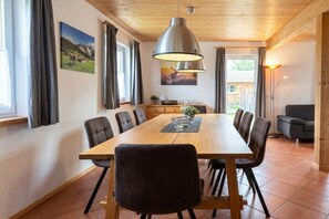 A dining area with a wooden table, chairs, and a pendant light. - Cabin in Annaberg with swimming pool (Annaberg)