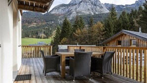 A wooden deck with a table and chairs, overlooking a mountainous landscape. - Cabin in Annaberg with swimming pool (Annaberg)