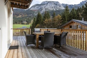 A wooden deck with a table and chairs, overlooking a mountainous landscape. - Cabin in Annaberg with swimming pool (Annaberg)