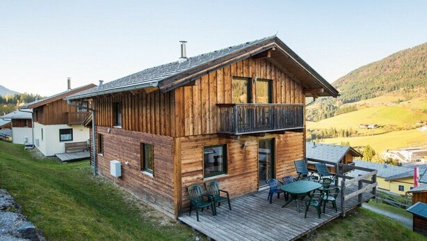 A wooden cabin with a balcony, a deck with outdoor furniture, and a view of the surrounding landscape. - Cabin in Annaberg with swimming pool (Annaberg)
