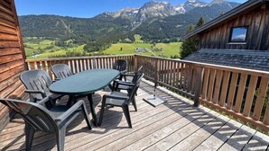 A wooden deck with a table and chairs, overlooking a mountainous landscape. - Cabin in Annaberg with swimming pool (Annaberg)