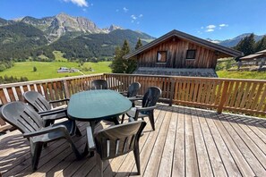 A wooden deck with a table and chairs, overlooking a mountainous landscape with a cabin. - Cabin in Annaberg with swimming pool (Annaberg)