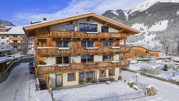 A multi-story wooden building with balconies, surrounded by snow-covered mountains.