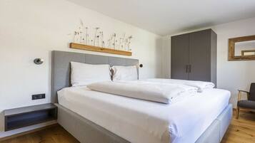 A modern bedroom with a bed, a bedside table, a wardrobe, and a wall-mounted shelf with dried flowers.