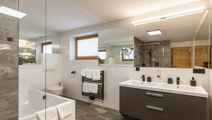 Ein modernes Badezimmer mit Duschkabine aus Glas, einer Badewanne, einer Toilette und einem Waschtisch mit Spiegel.