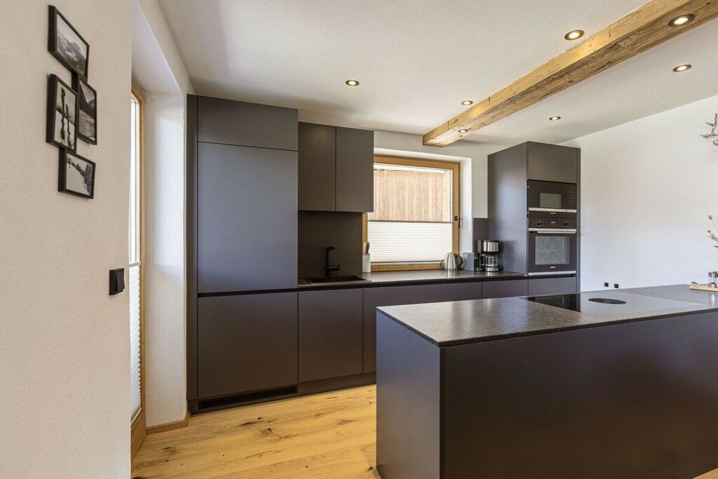 Una cocina moderna con armarios oscuros, una isla central y electrodomésticos integrados.