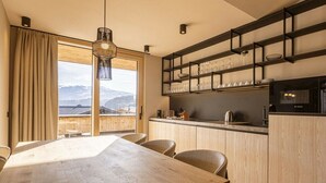 Eine moderne Küche mit Holzschränken, einer eingebauten Mikrowelle und einem Fenster mit Blick auf eine Berglandschaft.