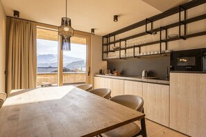 A modern kitchen with wooden cabinets, a built-in microwave, and a window overlooking a mountainous landscape. - Penthouse with 2 bedrooms (Oberndorf in Tirol)