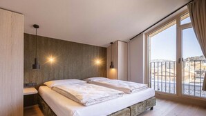 Ein Schlafzimmer mit einem Bett, Nachttischen und Blick ins Freie.