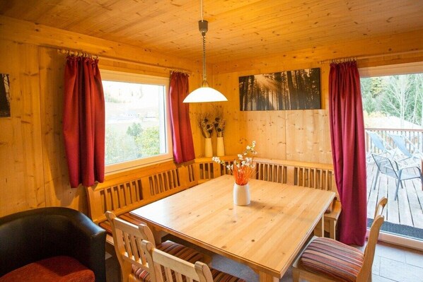 A wooden interior with a dining table, chairs, and a bench.