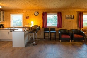 A wooden interior with a kitchen, bar area, and seating.