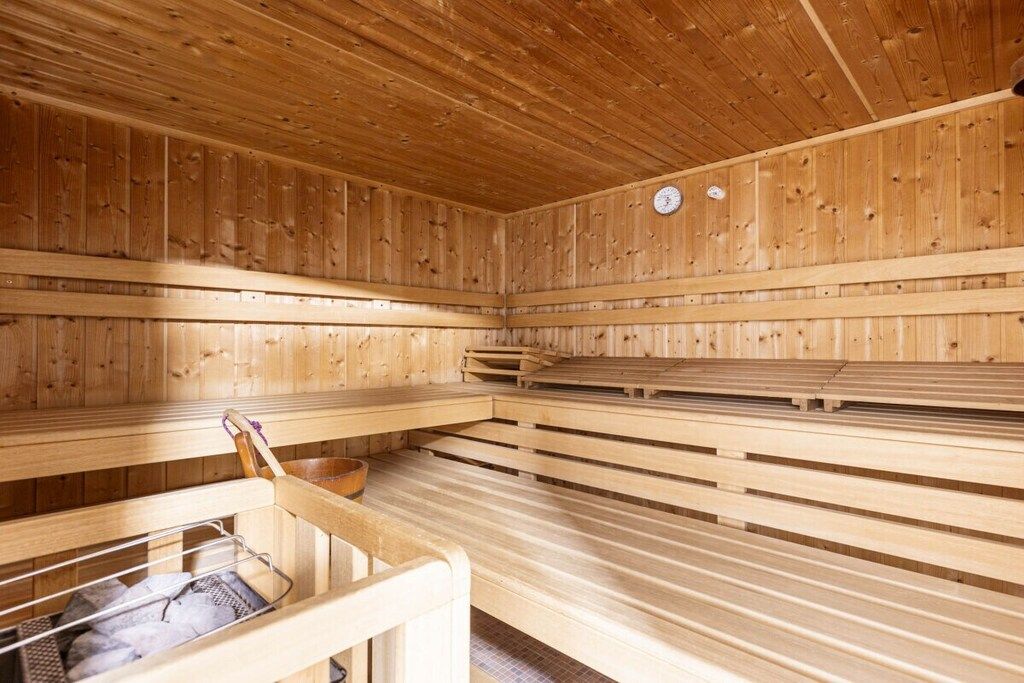 Una sauna con bancos de madera y un banco de metal con un perchero para toallas.