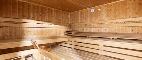 Una sauna con bancos de madera y un banco de metal con un perchero para toallas.