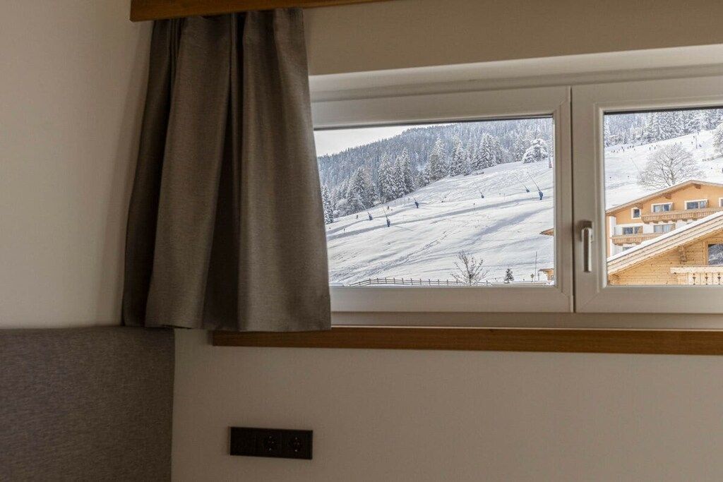 A window with a view of a snowy landscape and a building.