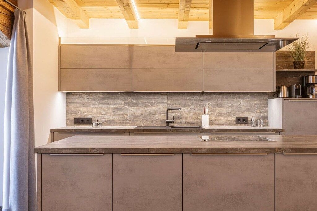 A modern kitchen with a central island, built-in cabinets, and a wooden ceiling.