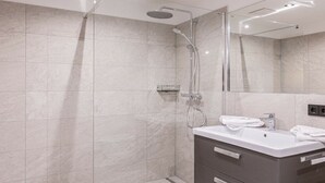 Ein modernes Badezimmer mit einer gläsernen Dusche, einem Waschtisch und einem Spiegel.