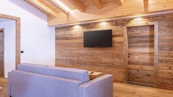 A modern interior with a wooden wall, a flat-screen TV, and a grey sofa.